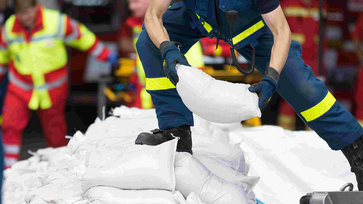 Katastrophenschutz: Helfer verlädt Sandsäcke.