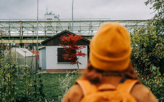 Wanderin blickt auf eine Gartenanlage am Rande eines Urban.Trails (Stadtwanderweg) im Ruhrgebiet