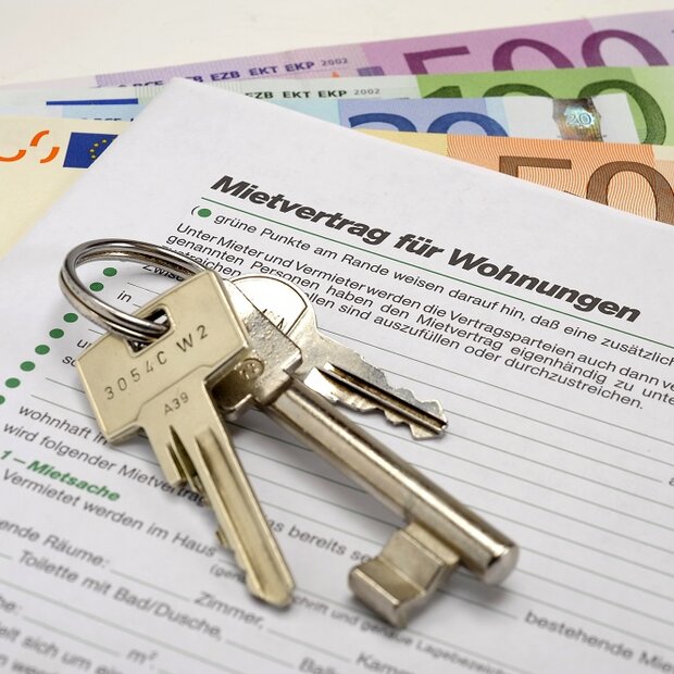 Ein Schlüsselbund liegt auf einem Mietvertrag und Bargeld.
