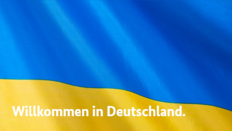 Schriftzug "Willkommen in Deutschland" über den Farben der ukrainischen Flagge