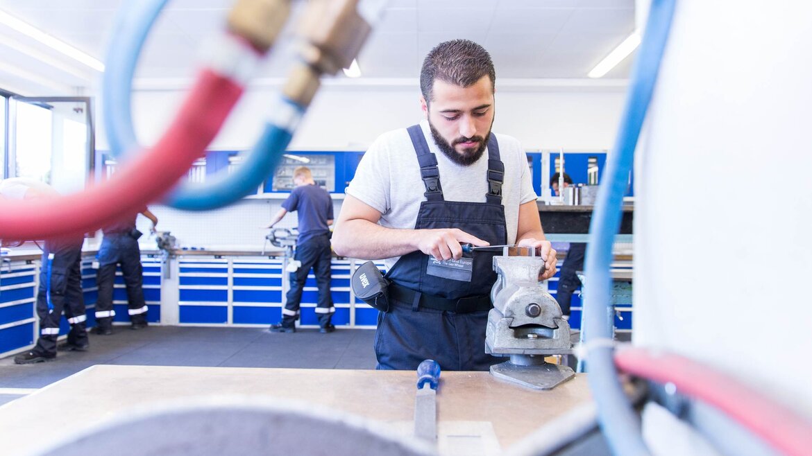 Geflüchteter arbeitet an Werbank in Werkstatt