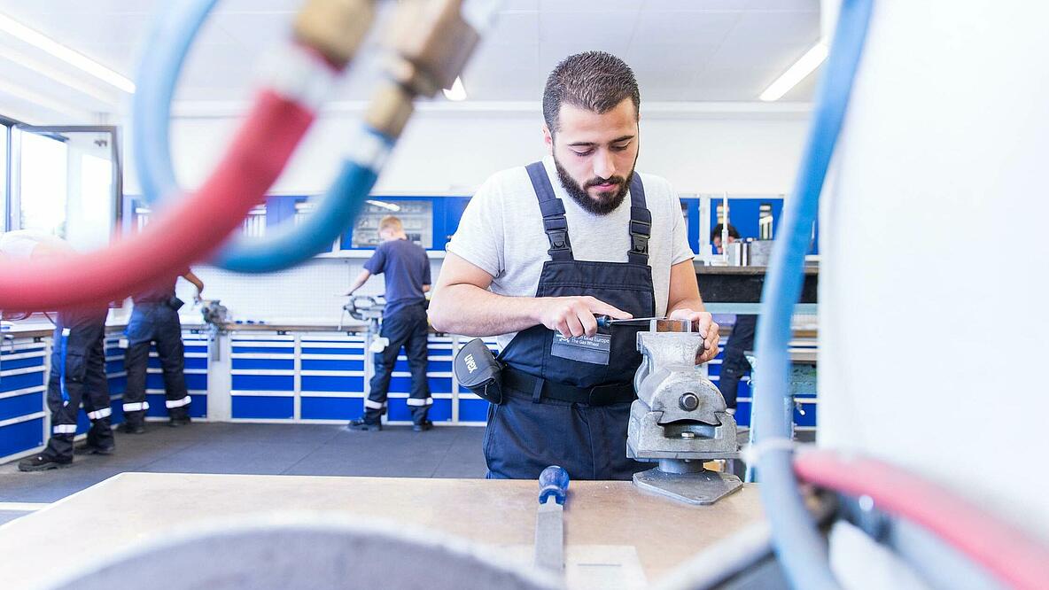 Geflüchteter arbeitet an Werbank in Werkstatt