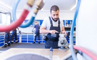 Geflüchteter arbeitet an Werbank in Werkstatt