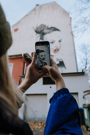 Wanderin fotografiert Wandbild (Mural) auf ihrem Weg auf einem Urban.Trail (Stadtwanderweg) im Ruhrgebiet